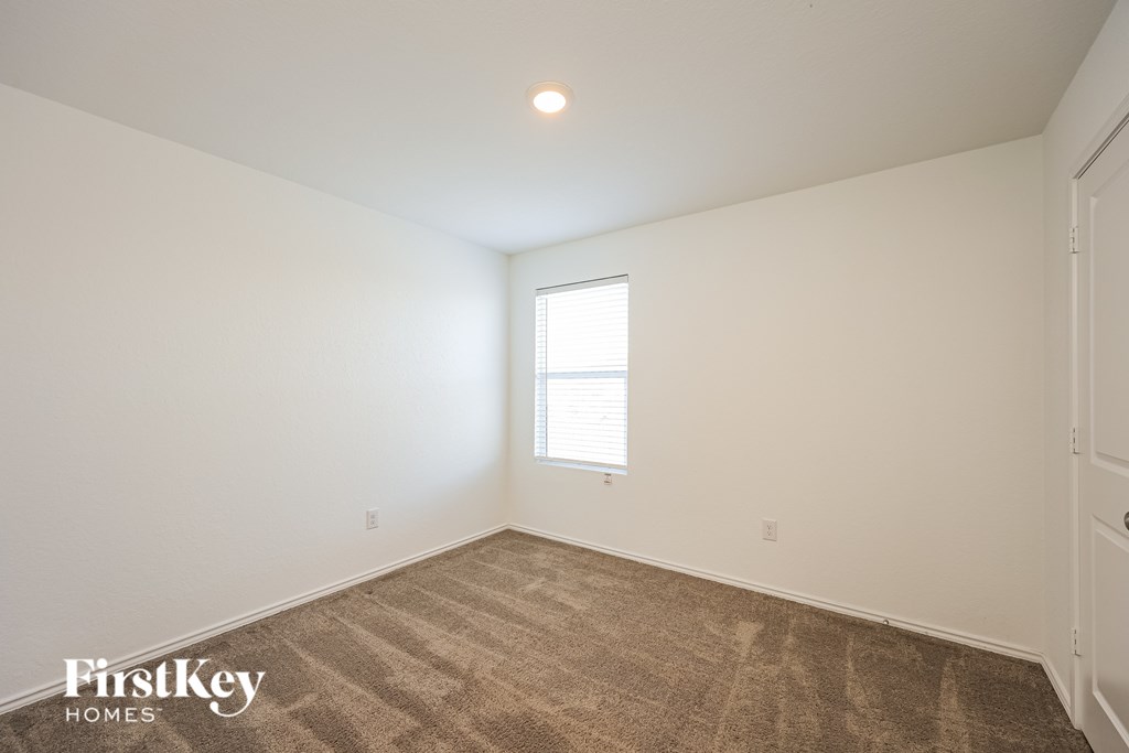 A room with a carpeted floor and a window with blinds.