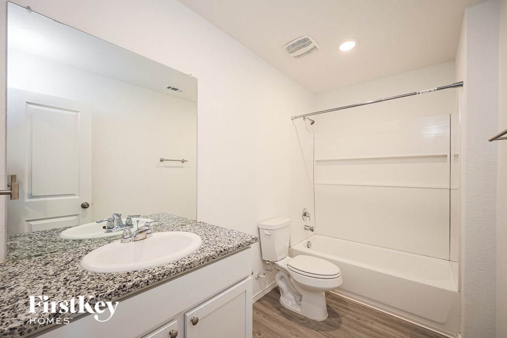 A bathroom with a granite countertop and white fixtures.