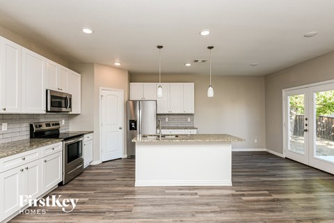A kitchen with white cabinets and a wooden floor.
