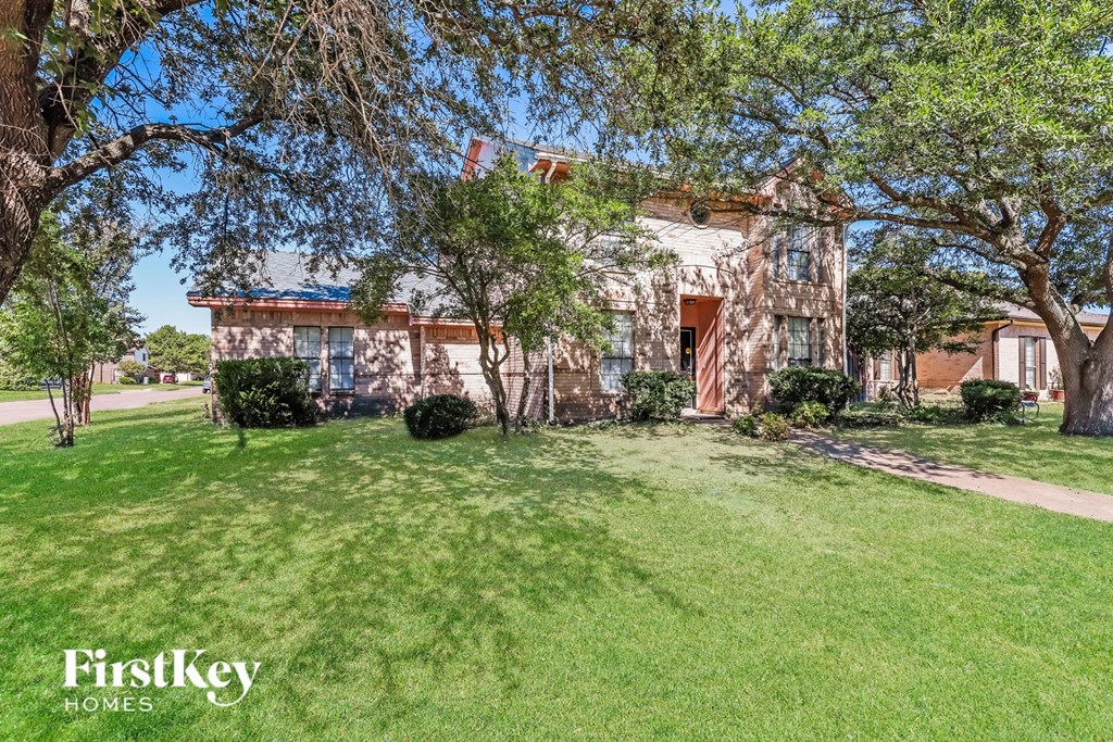 A house with a lawn and trees in front of it.