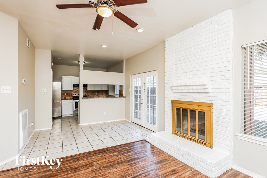 A spacious living room with a fireplace and a ceiling fan.