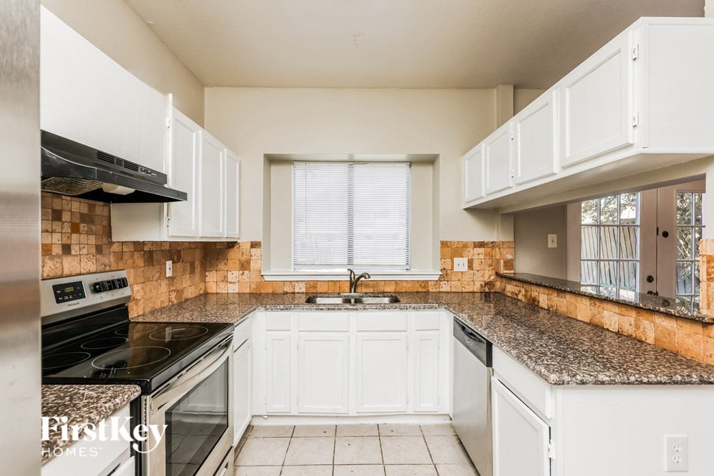 A kitchen with white cabinets and a tiled floor.