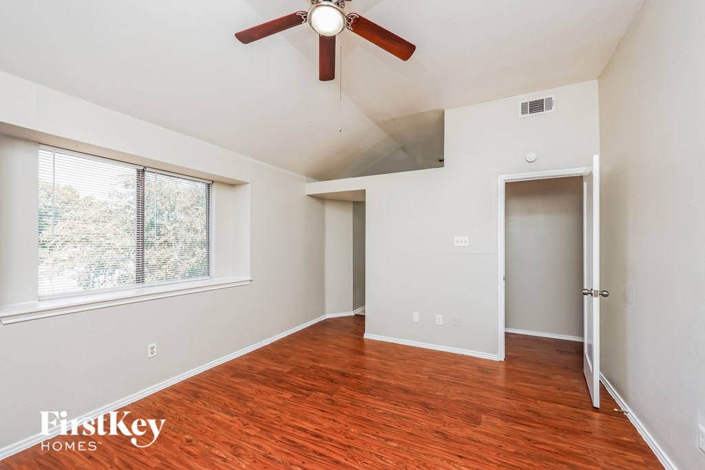 A room with a ceiling fan and wooden flooring.