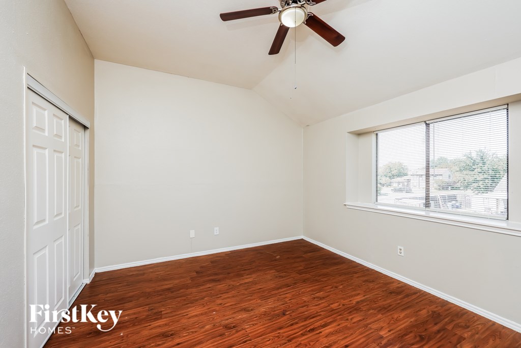 A room with a ceiling fan and a window with blinds.