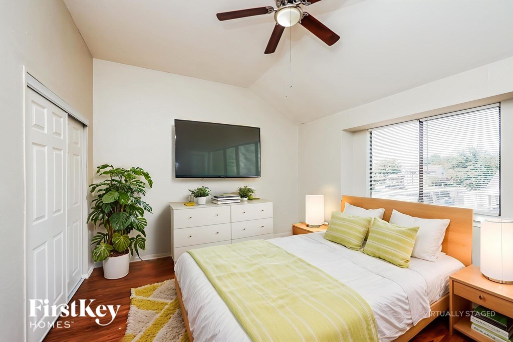A bedroom with a bed, a ceiling fan, and a television.