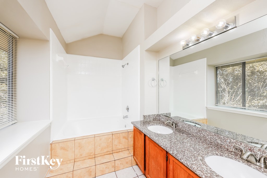A bathroom with a tiled shower and a granite countertop.