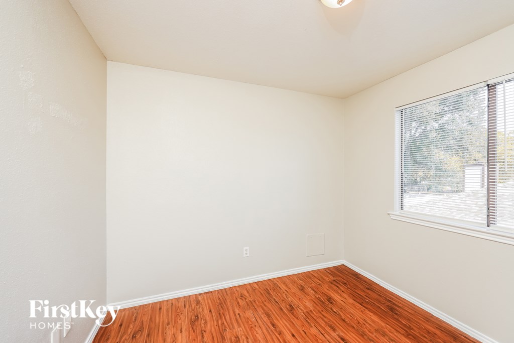 A room with wooden floors and a window with blinds.