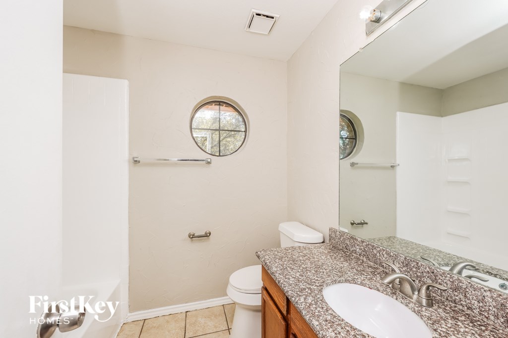 A bathroom with a toilet, sink, and mirror.
