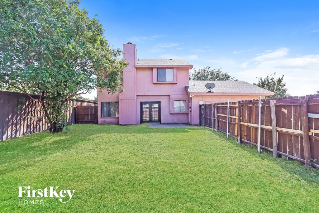 A pink house with a green lawn in front of it.