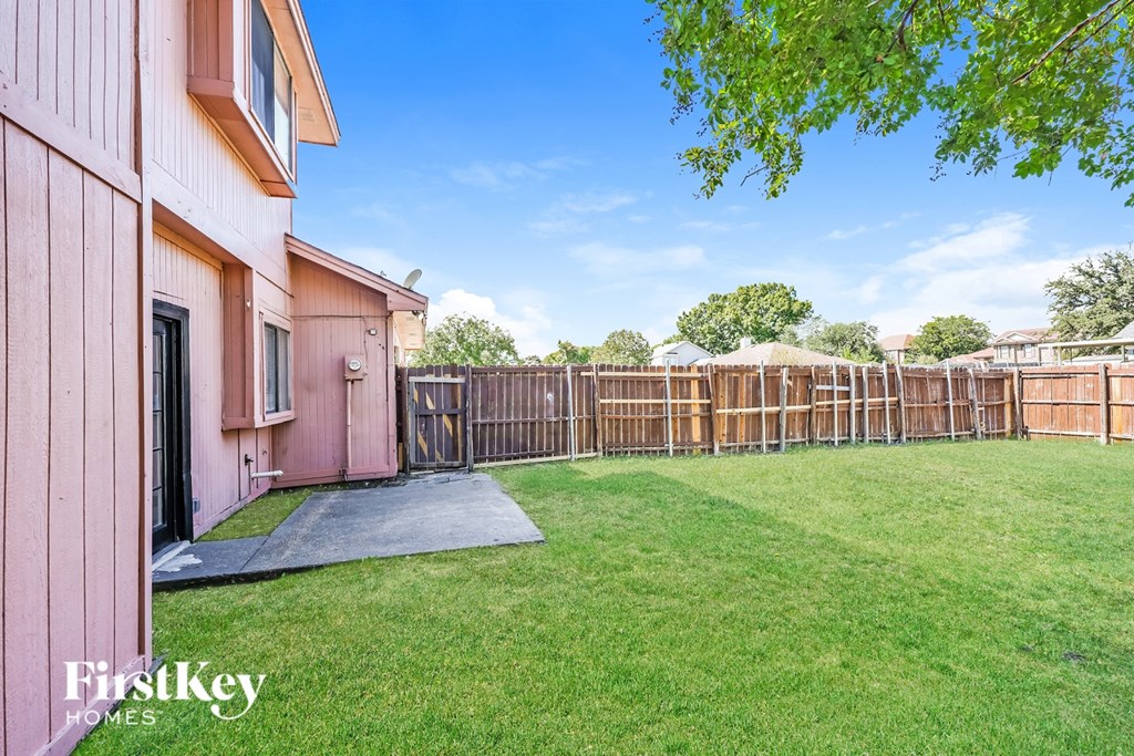 A pink house with a green lawn and a wooden fence.