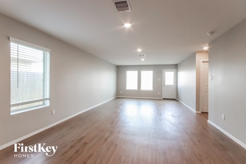 A spacious room with wooden floors and white walls.