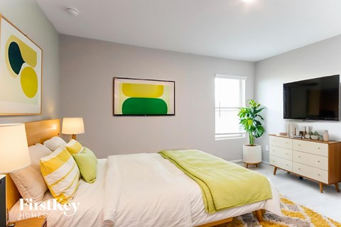 A bedroom with a bed, nightstand, and a painting on the wall.