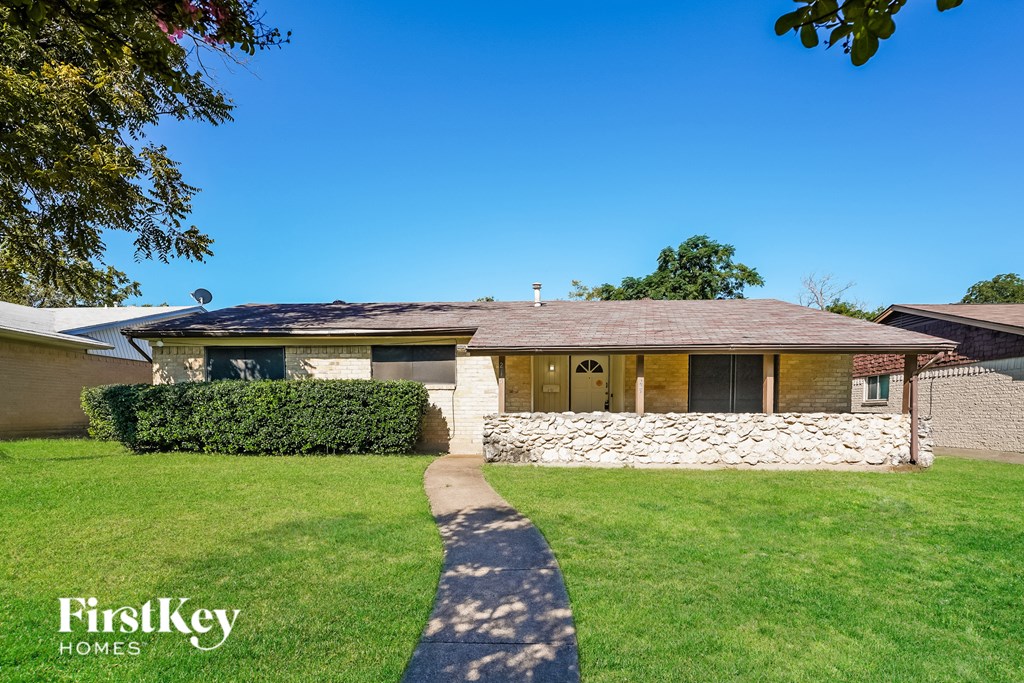 A house with a stone wall and a green lawn.