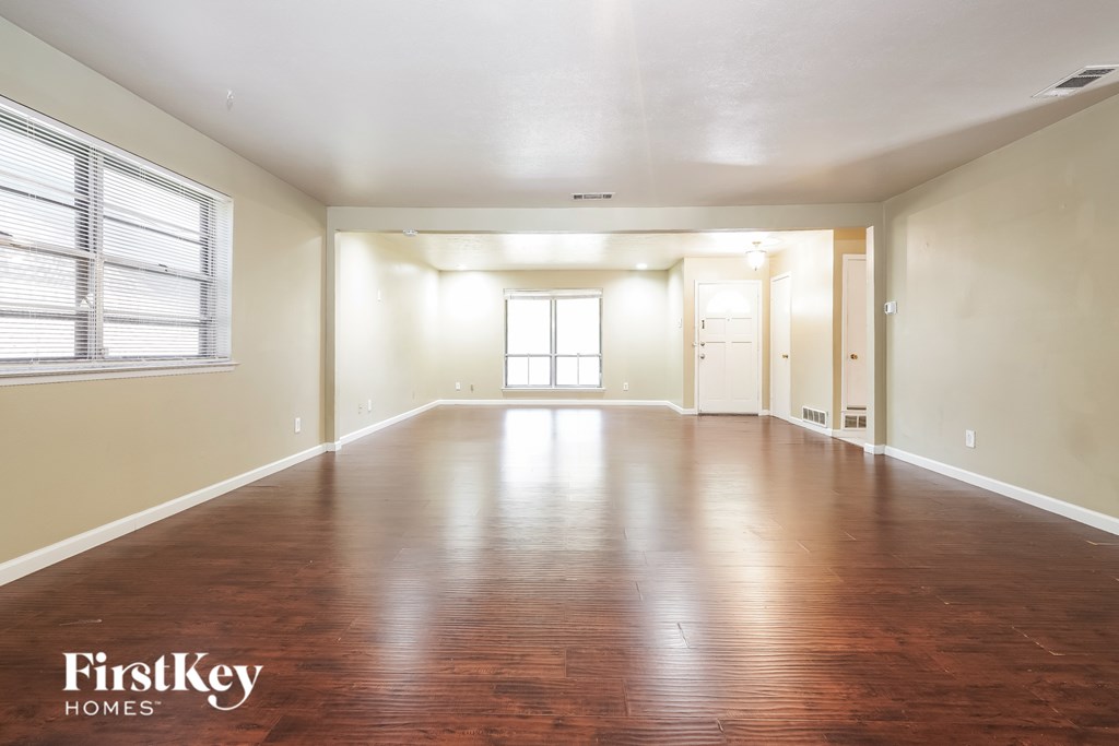 A spacious room with wooden floors and a large window.