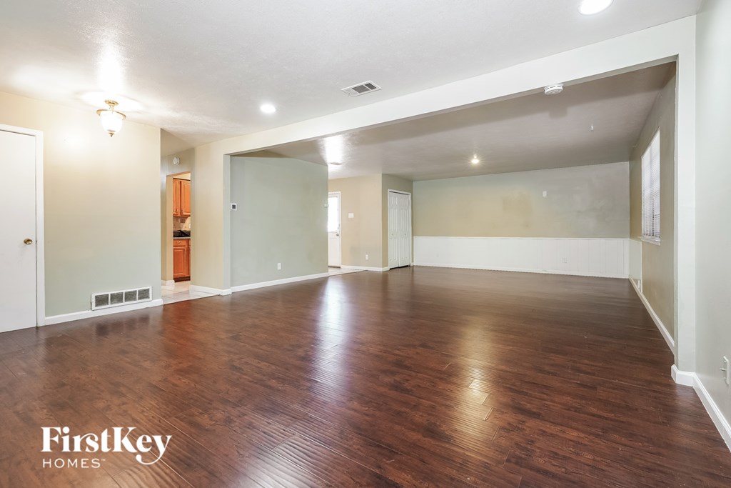 A spacious room with wooden floors and white walls.