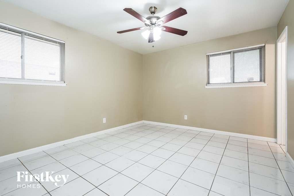 A room with a ceiling fan and two windows.