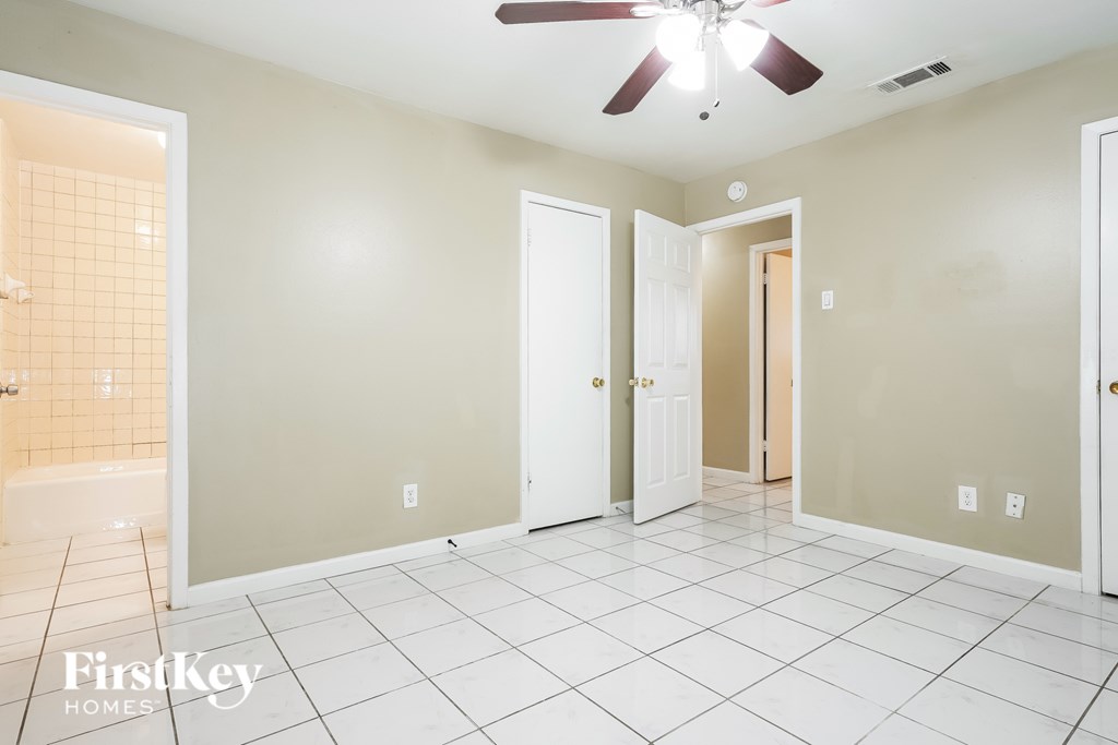A room with a ceiling fan and tile flooring.