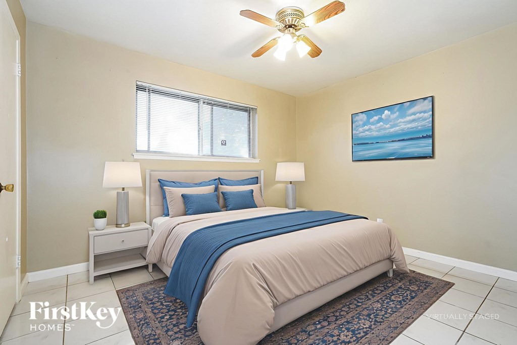 A bedroom with a bed, two lamps, and a painting on the wall.