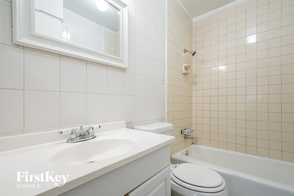 A white bathroom with a tub, toilet and sink.