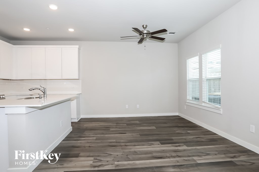 A spacious kitchen with a fan and wooden flooring.