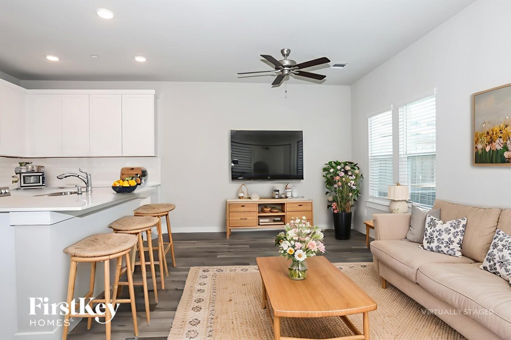 A well-lit, modern living room with a kitchen area in the background.