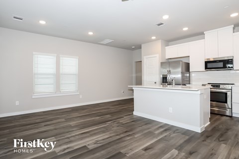 A kitchen with white cabinets and a wooden floor.
