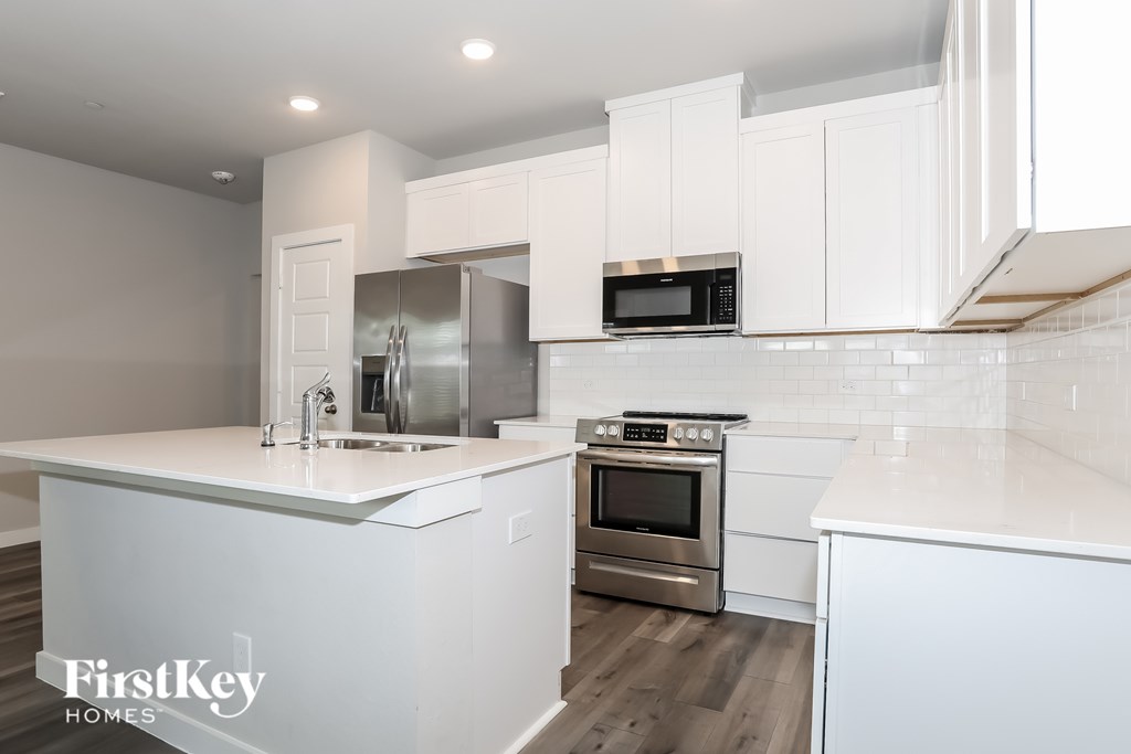 A modern kitchen with white cabinets and stainless steel appliances.