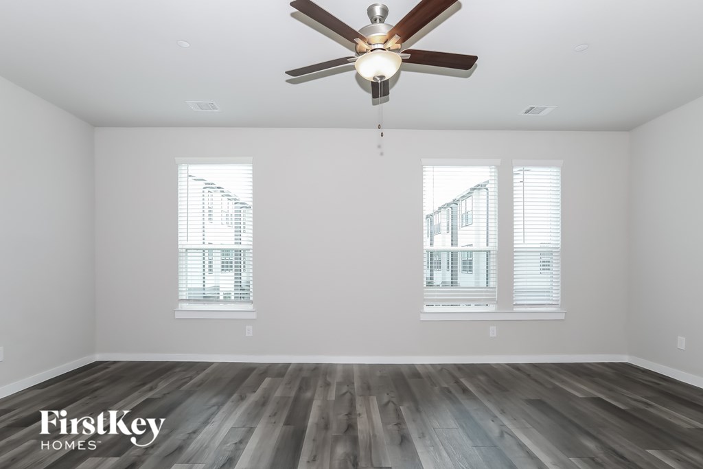 A room with a ceiling fan and wooden flooring.