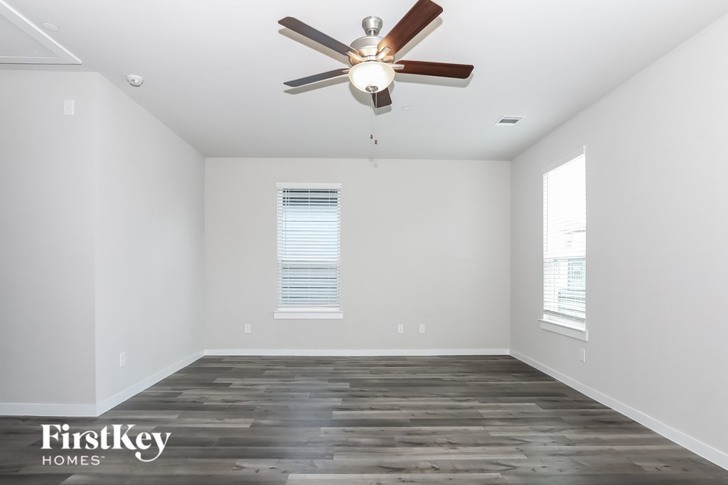 A room with a ceiling fan and wooden flooring.