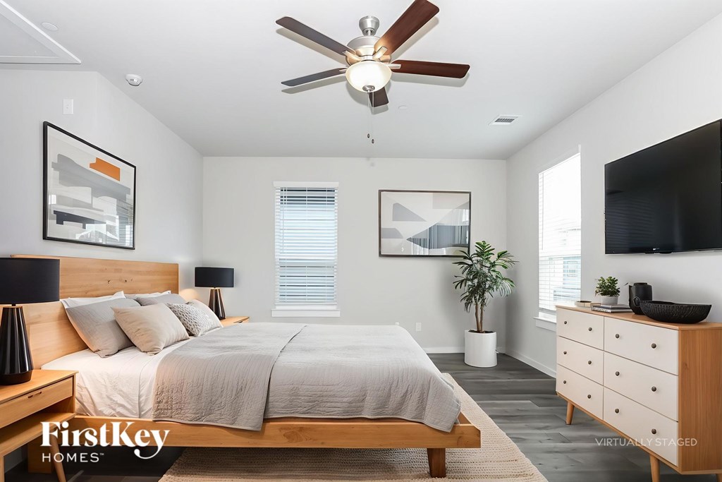 A bedroom with a bed, dresser, and ceiling fan.