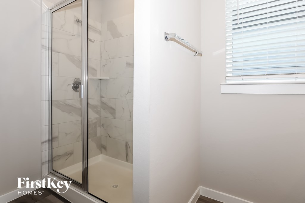 A white bathroom with a glass shower door and a FirstKey Homes logo.