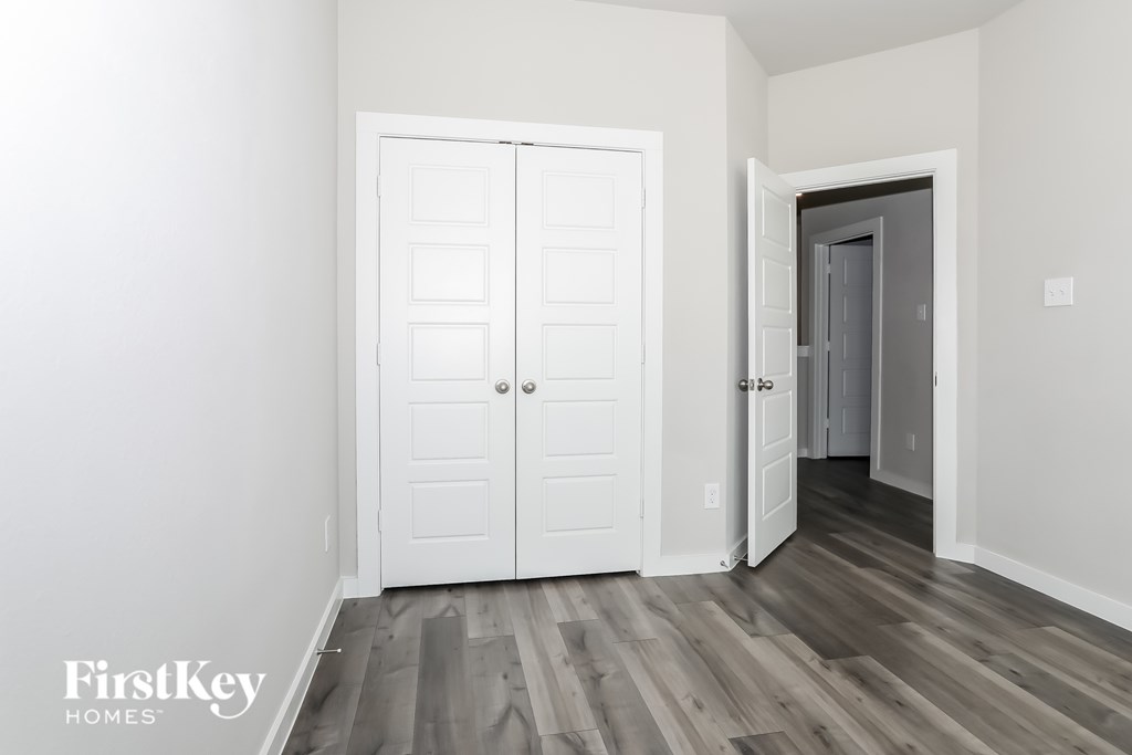 A white door with a small window is in a room with wooden floors.