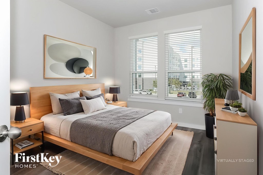 A bedroom with a large bed, a nightstand, and a mirror on the wall.