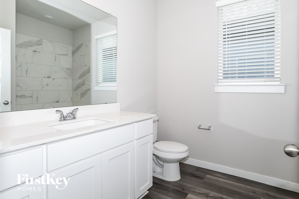A white bathroom with a toilet, sink, and a mirror.