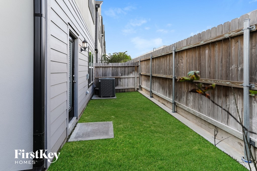 A backyard with a wooden fence and a green lawn.