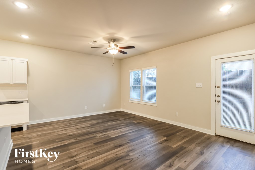 A spacious room with wooden flooring and a ceiling fan.