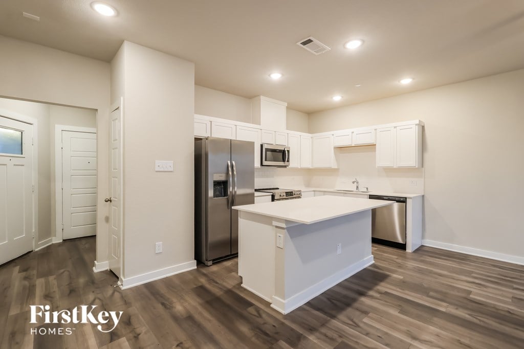 A kitchen with a refrigerator, microwave, and oven.
