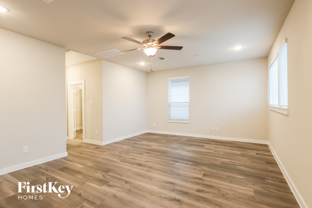 A spacious room with wooden flooring and a ceiling fan.