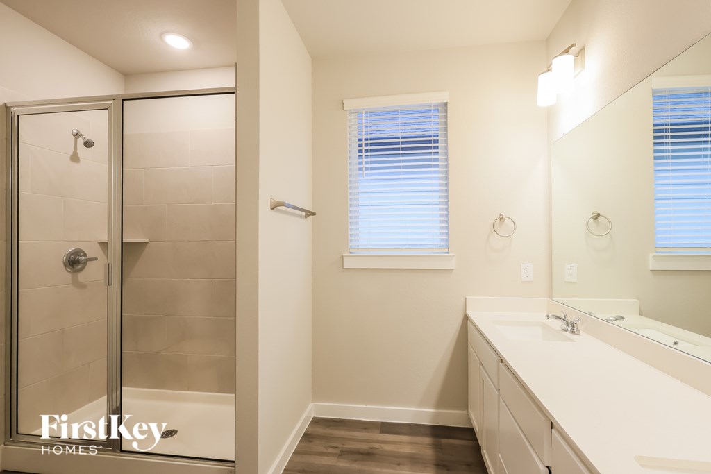 A bathroom with a white sink and a glass shower door.