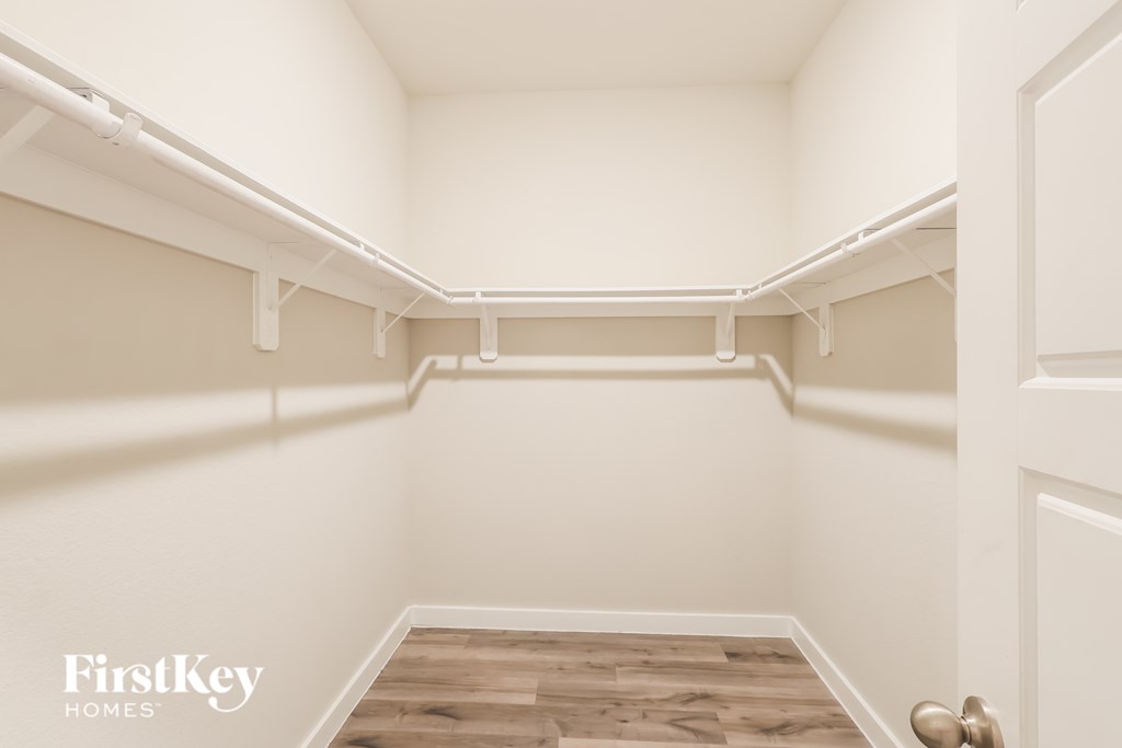 A white closet with a wooden floor and a white door.