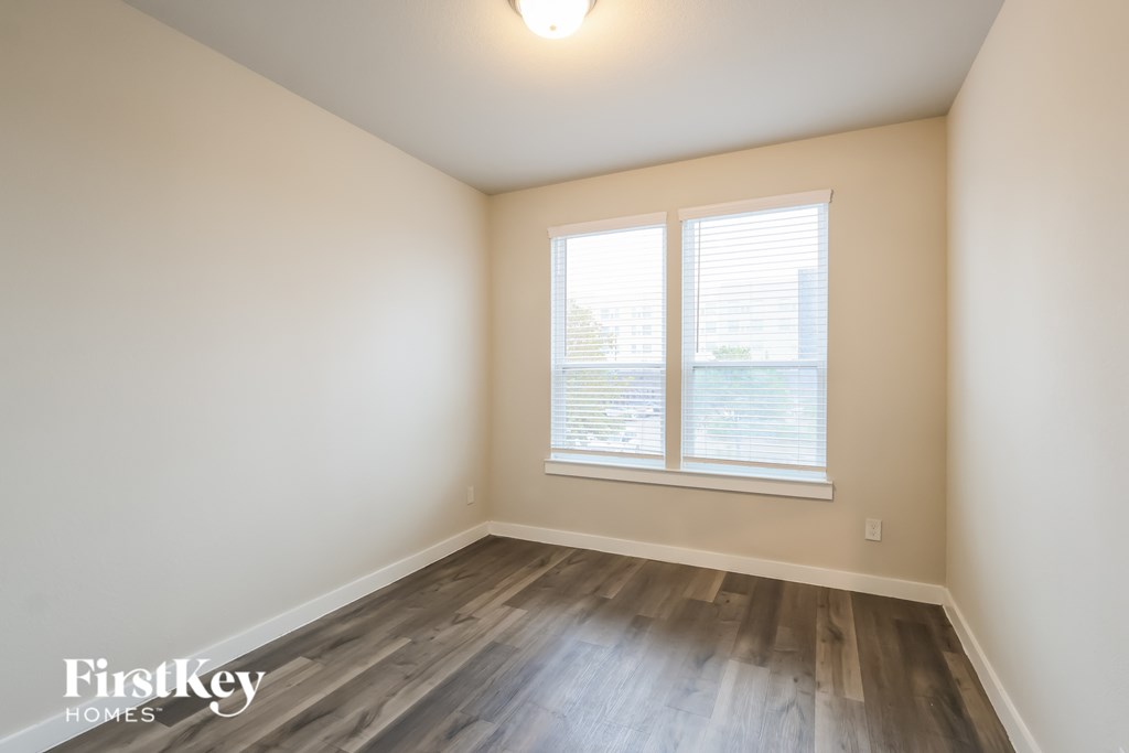 A room with wooden flooring and a window with blinds.