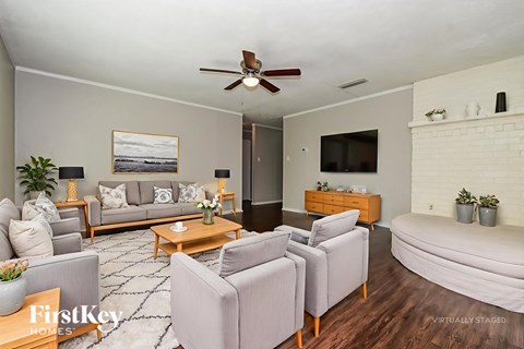 A living room with a grey couch, a coffee table, and a flat screen TV mounted on the wall.
