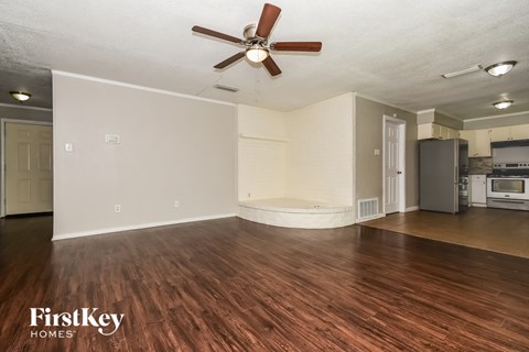 A spacious room with a wooden floor and a ceiling fan.
