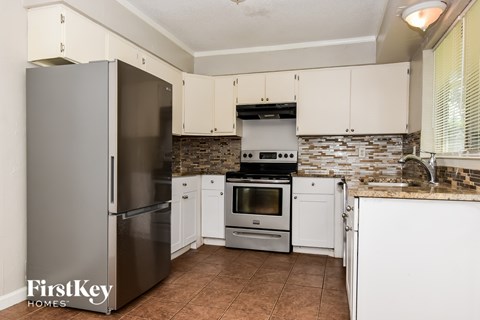 A kitchen with a refrigerator, oven, and cabinets.