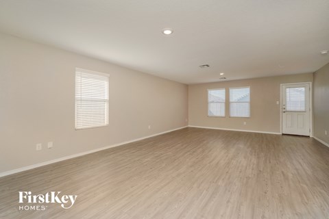 A spacious room with wooden flooring and a door on the right side.