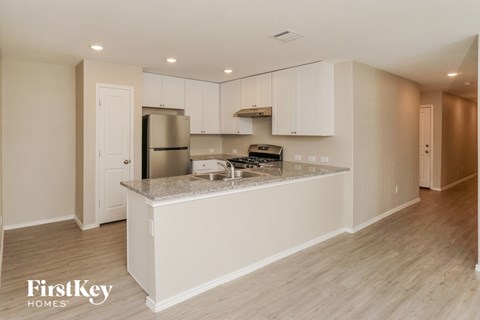 A kitchen with white cabinets and a granite countertop.