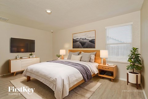 A bedroom with a bed, nightstands, and a plant.