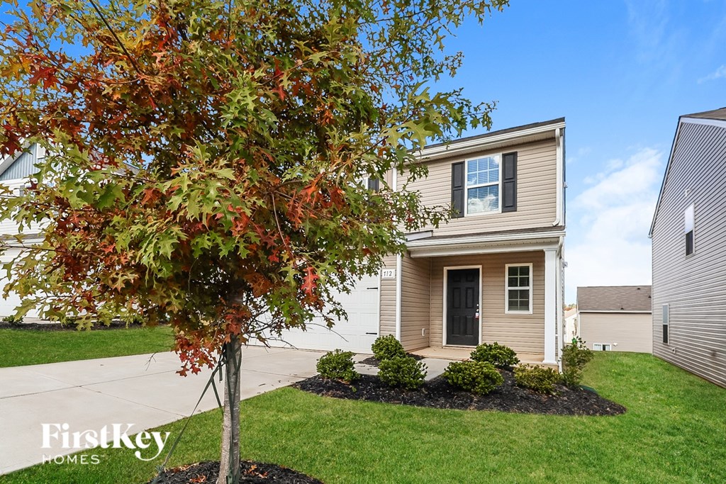 A tree with red leaves is in front of a house with a sign that says "FirstKey Homes".