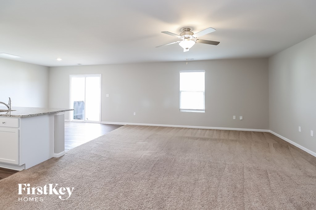 A spacious room with a carpeted floor and a ceiling fan.