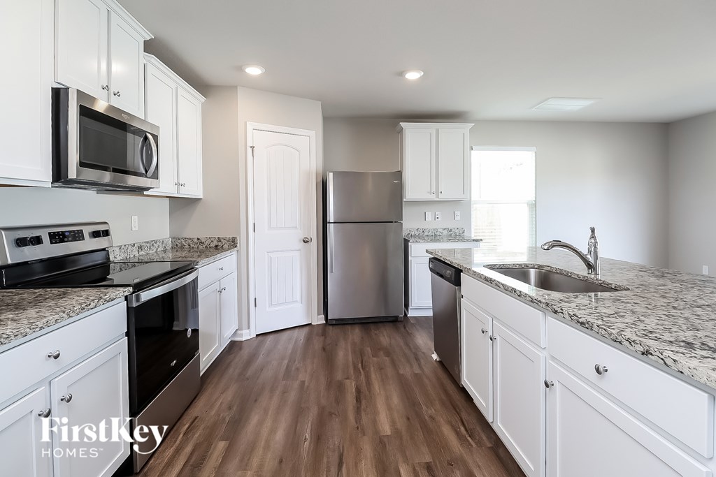 A kitchen with white cabinets and a granite countertop.
